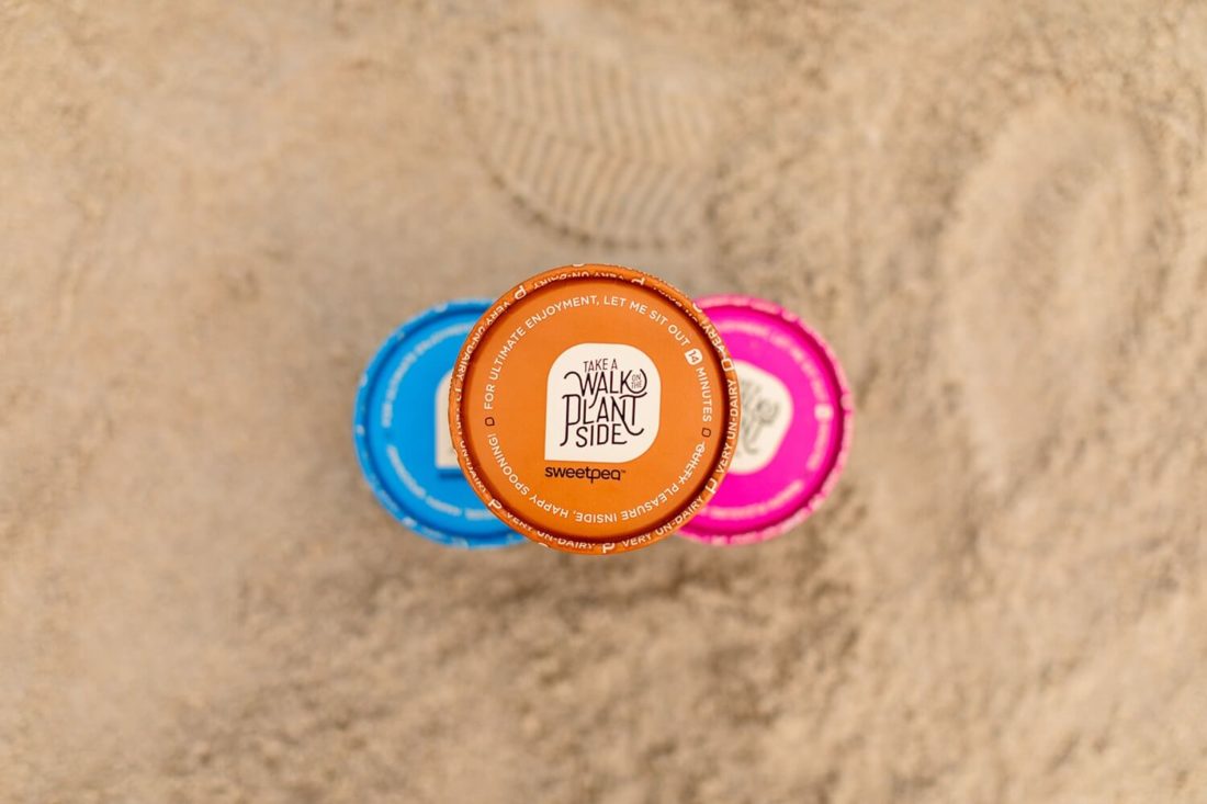 Overhead view of three pints of SweetPea plant-based ice cream stacked in a pyramid on the beach